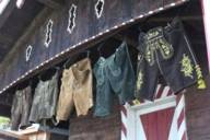 Various leather pants hanging from a wooden hut.
