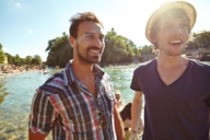 Two men are standing at the Isar River in Munich on a sunny day.