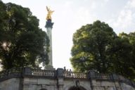 The golden statue of the Friedensengel statue stands among trees in the Bogenhausen district of Munich