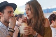 Une femme et un homme boivent avec des pailles dans une noix de coco au festival Tollwood à Munich.