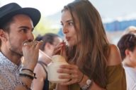 Una donna e un uomo bevono da cannucce da una noce di cocco al Tollwood Festival di Monaco.