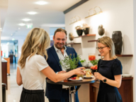 A man and two women eat snacks at a bar table during a congress in Munich.