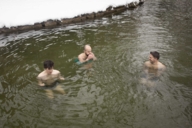 Three men ice bathing in the Eisbach in winter