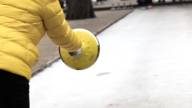 A person in a yellow jacket shooting curling stones.