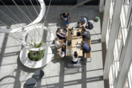 Working group at a wooden table in a light-flooded auditorium photographed from above