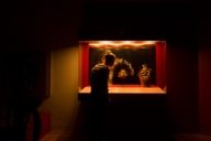 A woman is standing in front of a cabinet full of exhibits in the Museum Museum Fünf Kontinente in Munich.