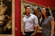 Una coppia cammina braccio a braccio attraverso l'Alte Pinakothek di Monaco di Baviera e guarda i dipinti.