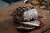 A juicy and crispy piece of roast pork on a kitchen board.