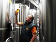 Steffen Marx, the founder of Giesinger Bräu in Munich, is standing in the brewery checking a glass of beer.