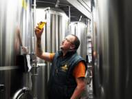 Steffen Marx is standing in a brewery checking a glass of beer.