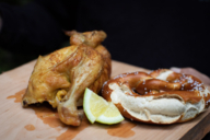 A crispy chicken with pretzel and lemon on a wooden plate in Munich.