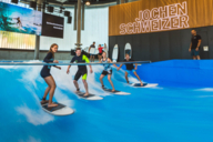 Four people surf a standing wave in the Jochen Schweizer Arena in Munich.