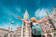 A woman stands with a backpack in front of the city hall in Munich.