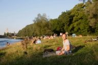 People are sitting on a sunny day at the Isar River Banks in Munich.
