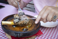 Someone is cutting a lamb shank with two forks.