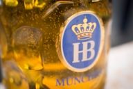 Sparkling beer in a glass jug with the logo of the Münchner Hofbräu brewery