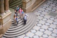 Picture of a guided tour of the Munich Palace of Justice. The group stands at the foot of the grand staircase in the central hall.