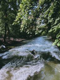 Eisbach surfers surf a wave in the English Garden in Munich.