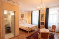 The royal suite of the Pension Bellevue, royally furnished with ornate elements, bed and sitting area.