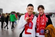 Chinese football fans are standing on the promenade in front of the Allianz Arena in Munich.