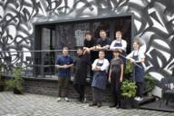 The team of the Mural Restaurant is gathered on the terrace in front of the restaurant.