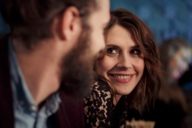 A woman is smiling at a man with beard in a bar in Munich.