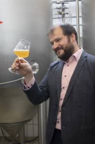 A man holds a glass of beer in his hand and looks at it.