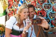 A couple is taking a selfie in front of gingerbread hearts at the Oktoberfest in Munich.