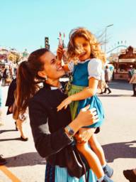 Carina and her daughter stand in the sunshine at the Oktoberfest in Munich.