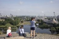 Tres turistas en el mirador de Olympiaberg con vistas al parque y al interior.