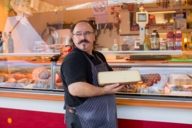 A salesman with a big piece of cheese in his hands at the weekly market at Hans-Mielich-Platz in Munich.