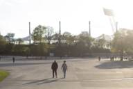 Two people in conversation take a walk through the Olympic Park.