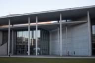 Museum façade of glass and concrete with isolated people.