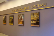 La scritta dorata della Pinacoteca di Dachau sopra quattro dipinti della mostra