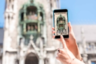 A woman is taking a picture of the Glockenspiel at Neues Rathaus in Munich.