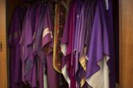 Various red and purple talars hang in an open cupboard.