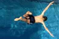 Boy jumping into a swimming pool.