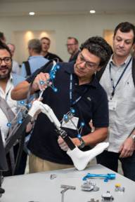 A man shows visitors at the ISAKOS congress medical tools on a robot.