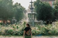 A woman is standing in front of a fountain on Weißenburgerplatz in Munich