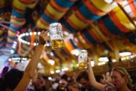 Women with beer mugs toasting in the Schützenzelt at the Oktoberfest in Munich