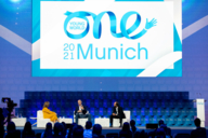 Three people discuss on the podium of the One Young World Summit in Munich.