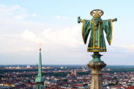 Statue of the Münchner Kindl on top of the Neues Rathaus tower photographed from behind from the air with a drone