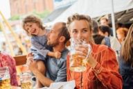 A women is drinking beer out of a beer mug at the Auer Dult in Munich.