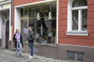 A man and a woman stand in front of a flower shop in autumn and talk.