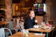 A young woman sits smiling in a restaurant in Munich.