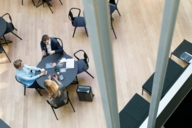 Two women and a man are sitting at a table in a foyer of a hotel in Munich. 