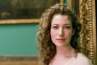 Closeup of a woman with curly hair in front of paintings at Sammlung Schack in Munich.