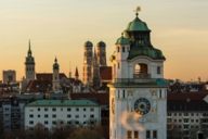 Panoramic view of the inner city of Munich at sunset with the Müller'sches Volksbad in front and the towers of St. Peter, Heilig-Geist-Kirche and Frauenkirche in the background.