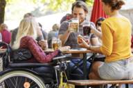A wheelchair user and two other people are in the Viktualienmarkt beer garden.