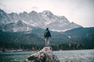 A man is standing on rocks at the shore of Eibsee nearby Garmisch in the surrounding region of Munich.